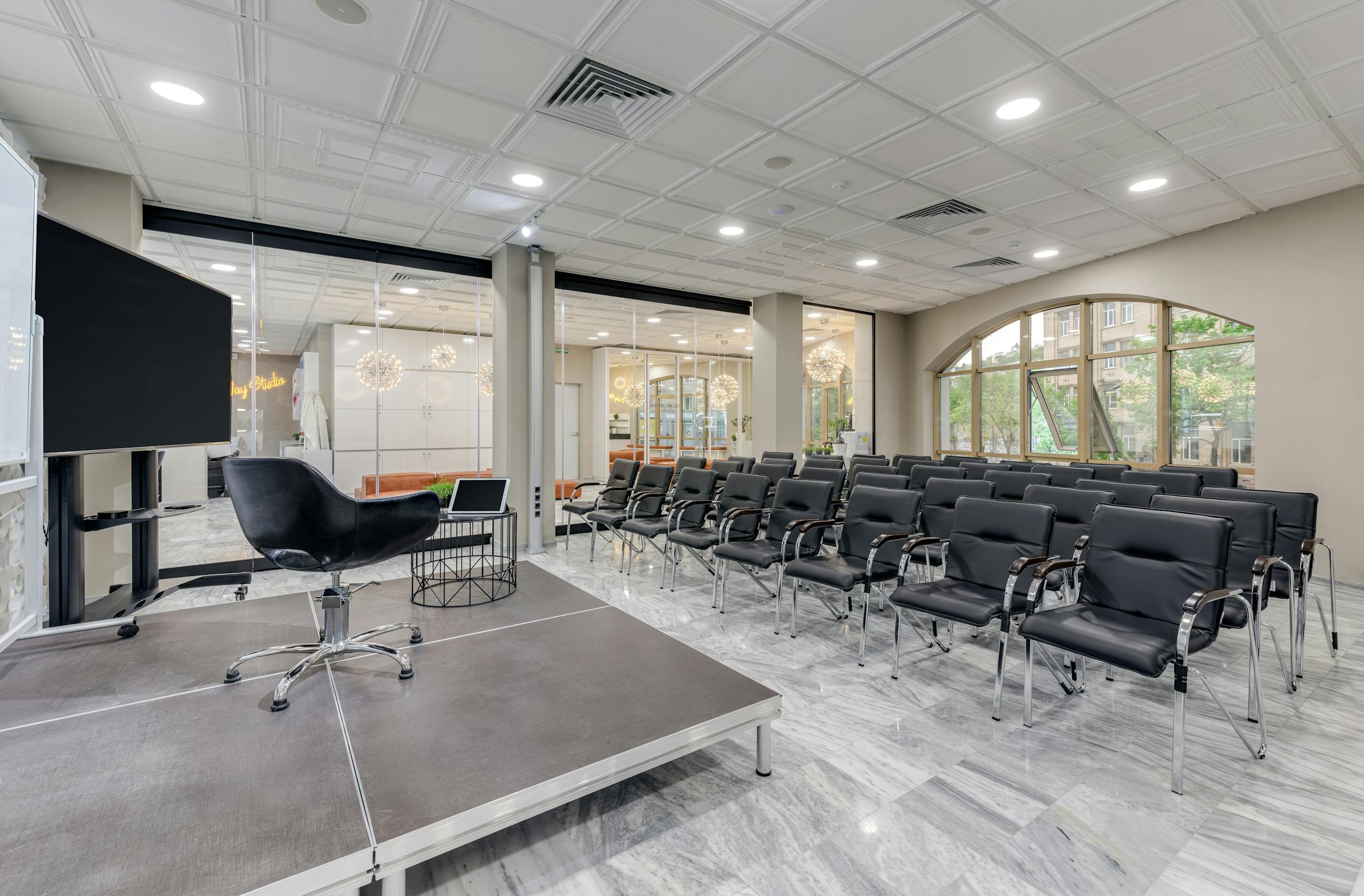 Spacious office setup with black chairs and a presentation stage.