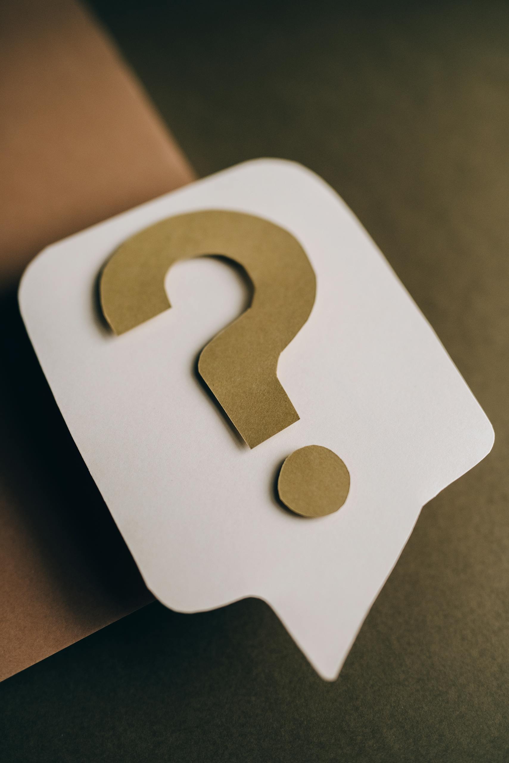Artistic paper craft of a question mark symbol on a textured green surface. Ideal for conceptual projects.